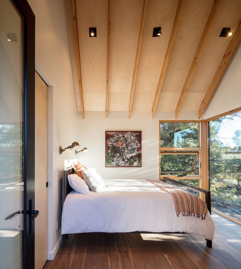 The bedroom in this modern cabin has views of the trees outside. #ModernCabin #Bedroom