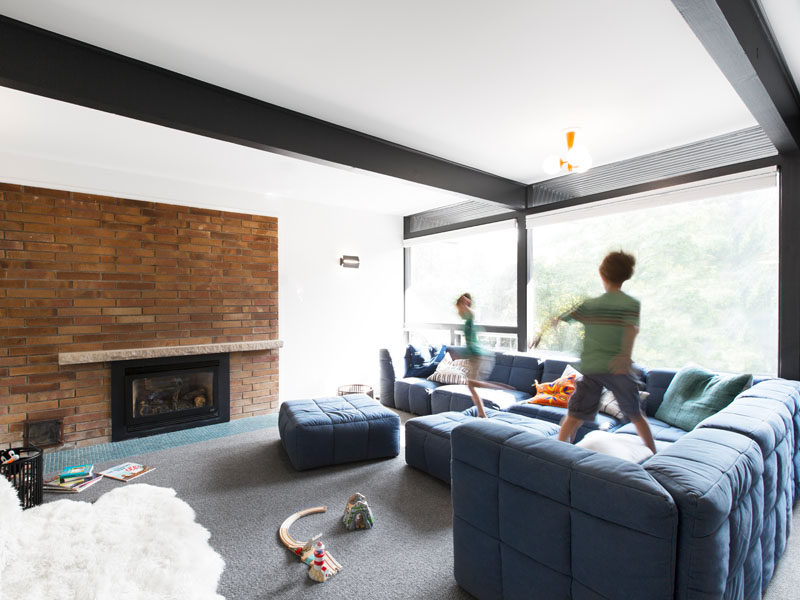 In this media room, a big comfortable blue couch runs alongside the large windows. #MediaRoom #ExposedBlackBeams