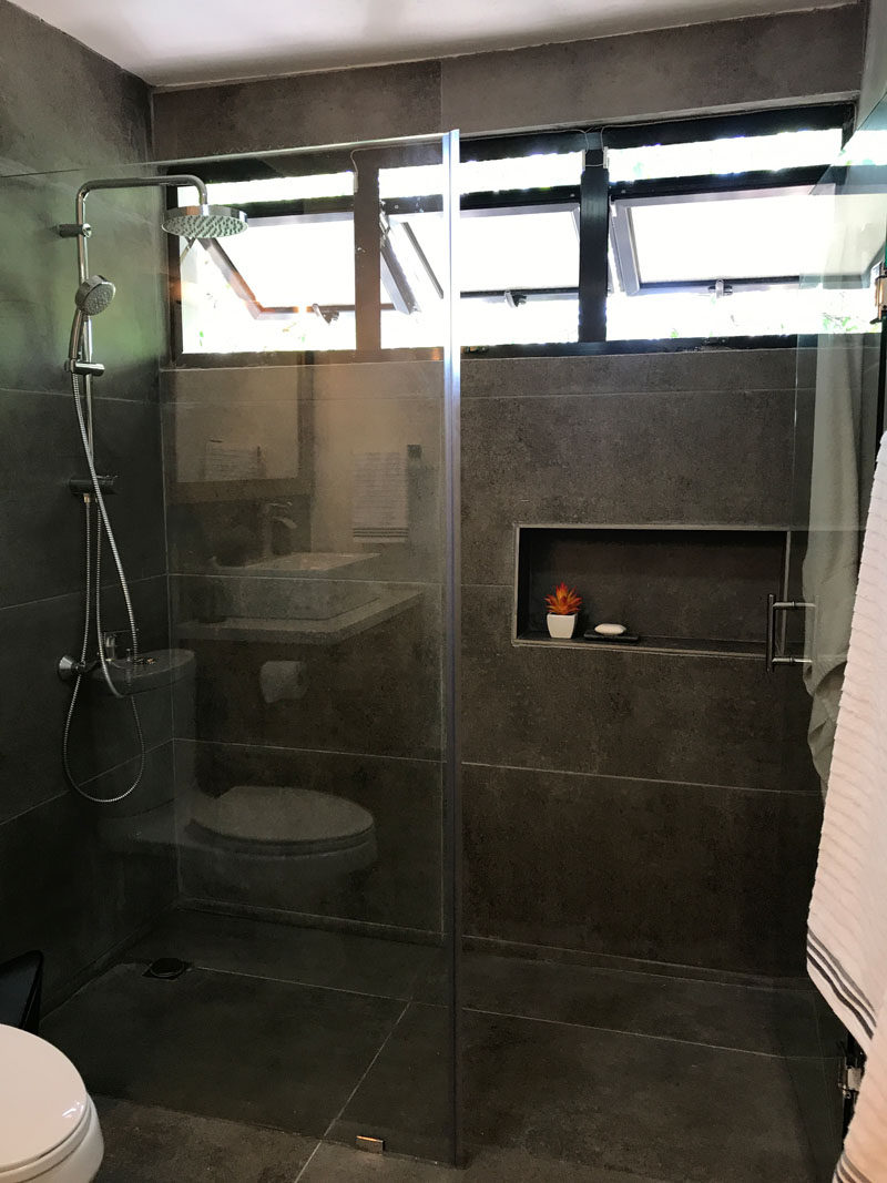 This renovated bathroom has glass shower surround and three outward opening windows at the top of the shower, that allow the light to travel throughout the small space. #UpdatedBathroom #GlassShowerSurround