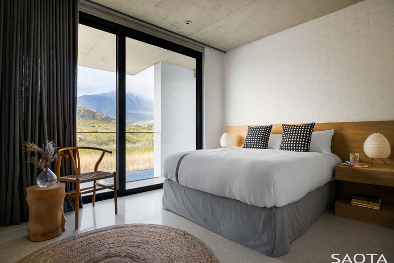 A wood headboard, chair and side table add a natural touch to this contemporary bedroom. #BedroomDesign #InteriorDesign