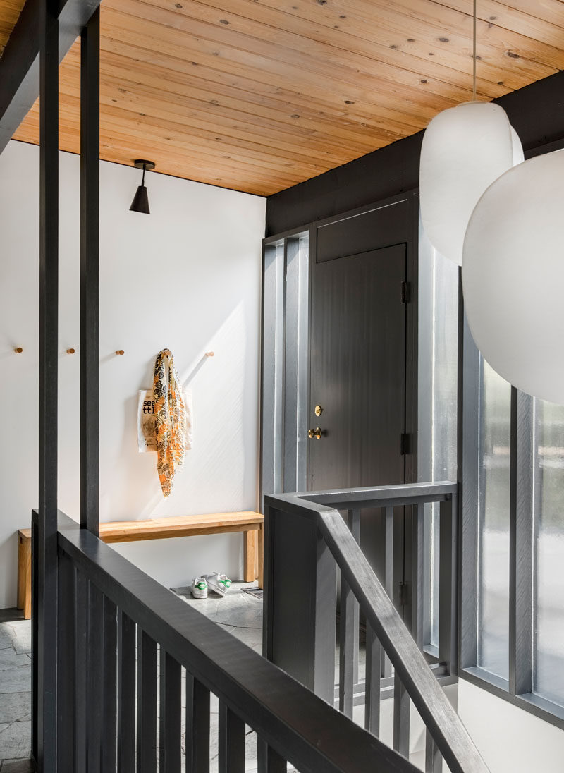 A black front door welcomes you to the home, that features a wood ceiling and exposed beams. #BlackFrontDoor