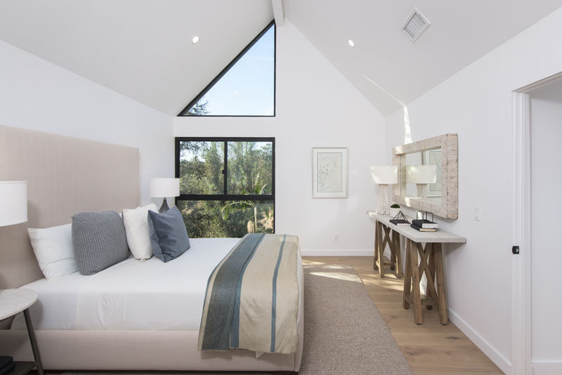 This contemporary bedroom features a vaulted ceiling, and a triangular window that draws your eye upwards to the height of the room.