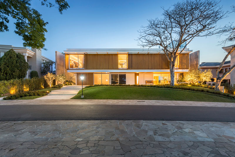 This modern Brazilian house has wood shutters on the upper level of the home that blend in with the facade when they're closed. #Shutters #ModernHouse #Architecture