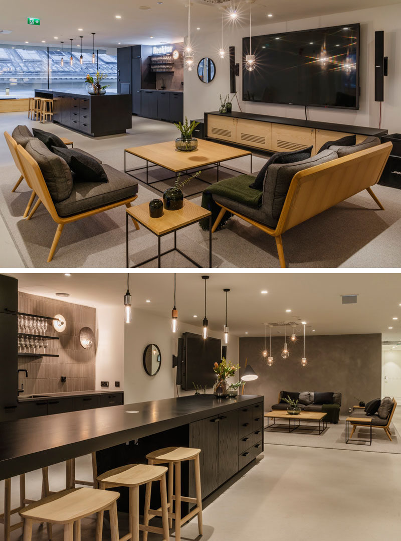 This modern offices features a dark kitchen with a long island, and a separate 'living room' like area for employees to relax. #Workplace #Kitchen #OfficeDesign