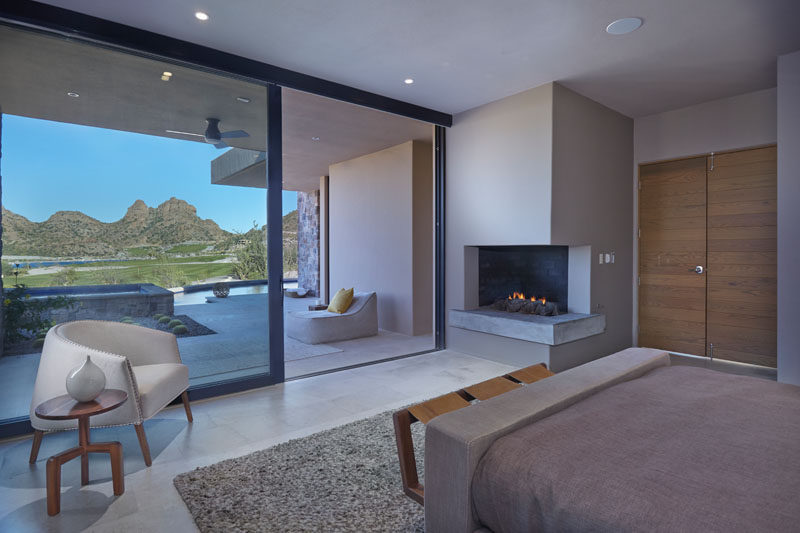 There's a corner fireplace in this modern master bedroom, and a sliding glass door opens up to a patio. #CornerFireplace #MasterBedroom #SlidingGlassDoor