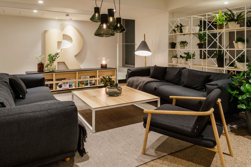 This modern office has a lounge area with comfortable dark couches and a light wood coffee table. #Workplace #OfficeDesign #LoungeArea