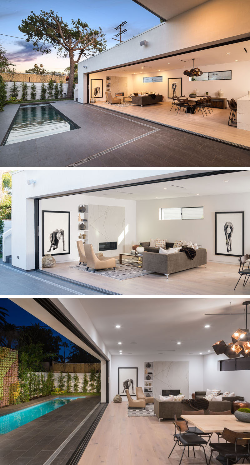 This modern house features living spaces that have all been designed to open it up to the outside by the use of sliding glass walls. At one end of the open interior is the living room that's focused on the fireplace. #ModernInteriorDesign #SlidingGlassWall