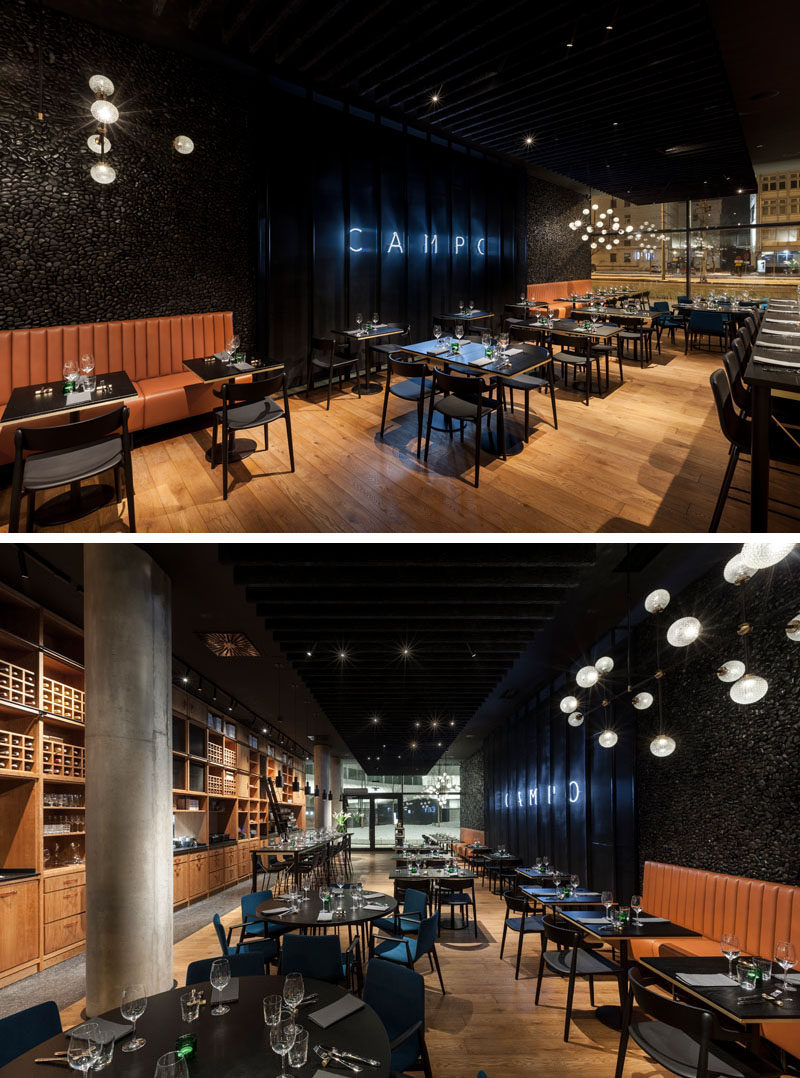 This modern restaurant features an open plan dining room, with dark colors and natural materials, like wood, leather and stone. #ModernRestaurant #RestaurantDesign