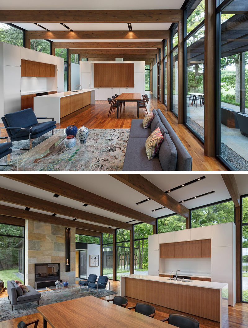 This modern house has walnut flooring, exposed wood beams, white walls and a bluestone fireplace. #InteriorDesign #KitchenDesign #Fireplace