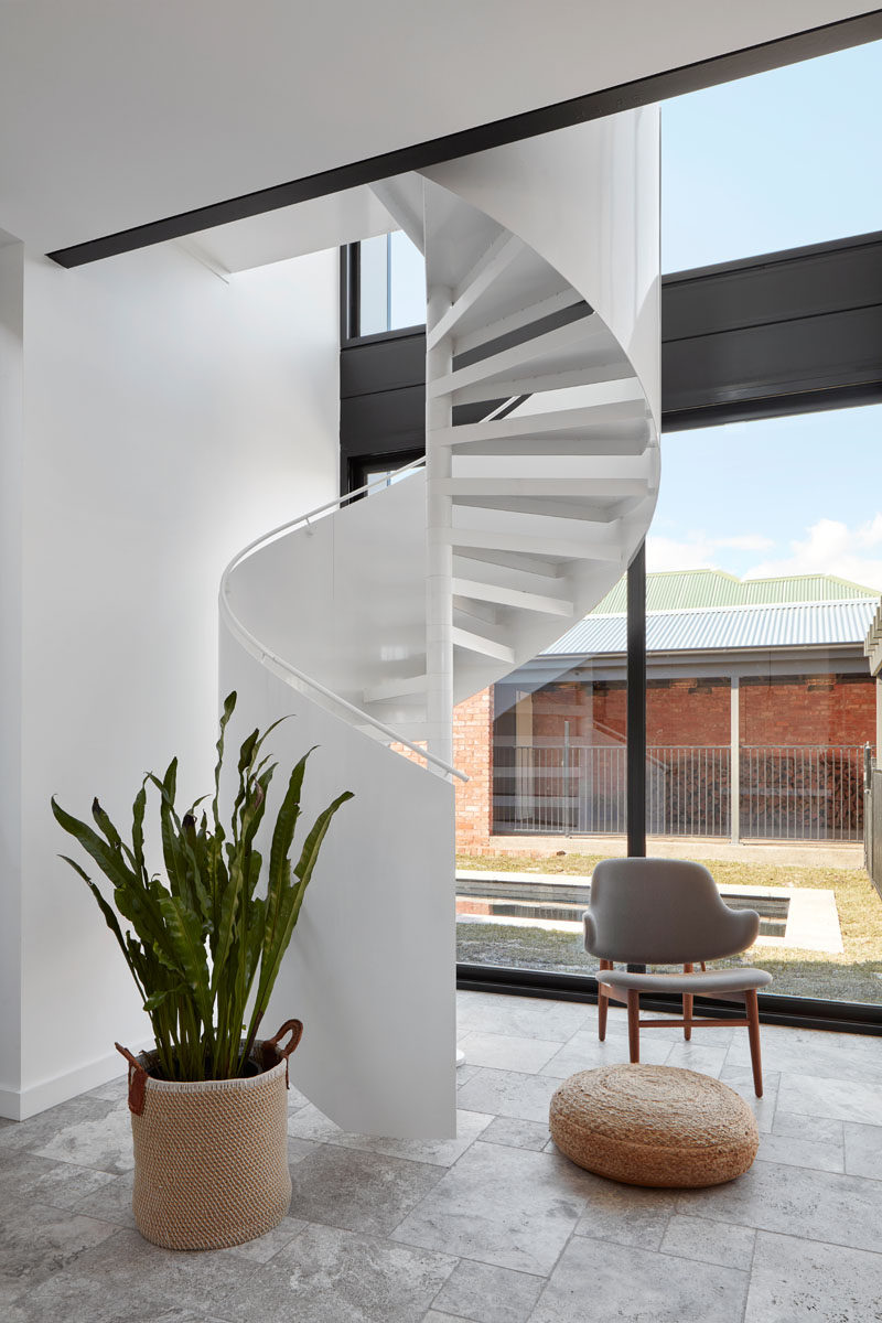 Travertine silver tiles in a French Pattern cover the floor of this modern house extension, and a white Enzie spiral staircase makes a striking statement in the room and leads up to a mezzanine master suite. #SpiralStairs #TravertineFlooring