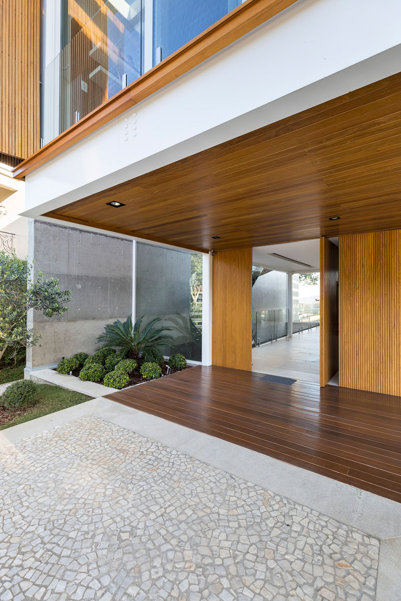 This modern house has a pivoting wood front door that matches the wood used on the upper level of the home. #ModernFrontDoor #WoodFrontDoor #PivotingFrontDoor