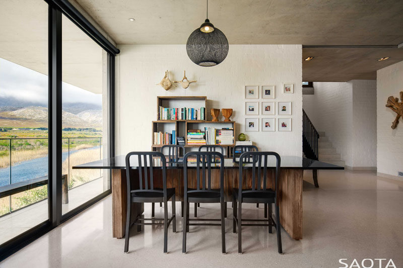 This modern house has a table that sits next to a bookshelf, making it the perfect spot for reading or playing games. #GamesRoom #InteriorDesign