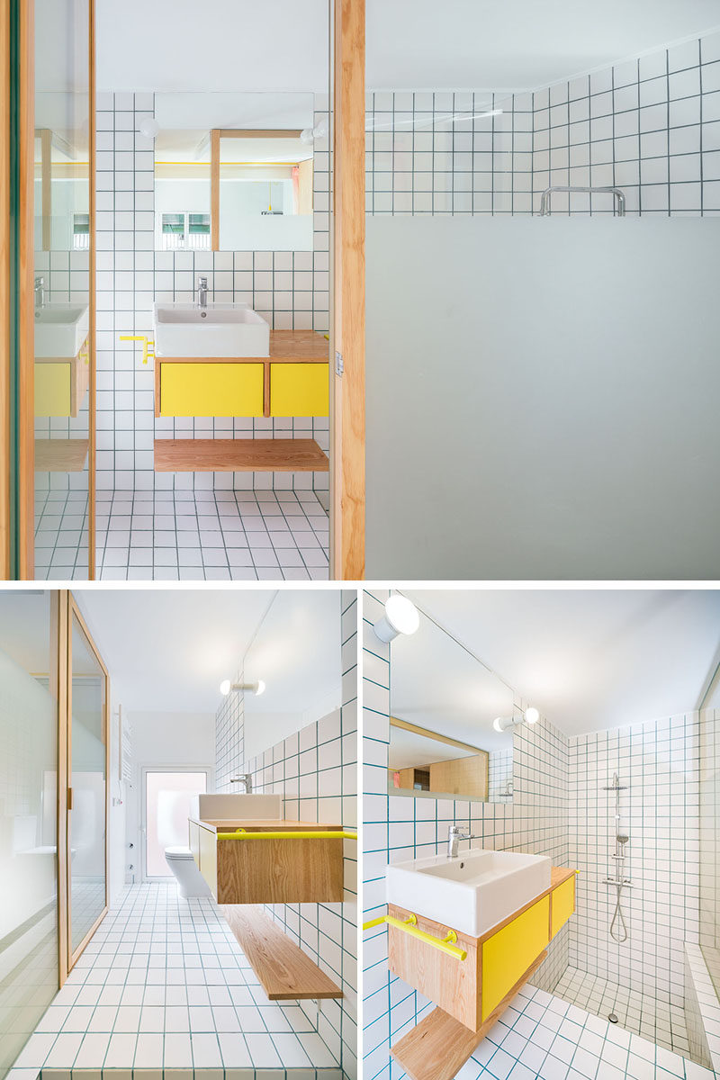 A partially frosted glass wall allows light to travel through to this long and narrow bathroom, however it also provides a degree of privacy. At one end of the bathroom is the toilet, while the other end is dedicated to a sunken bathtub and shower. #Bathroom #ModernBathroom