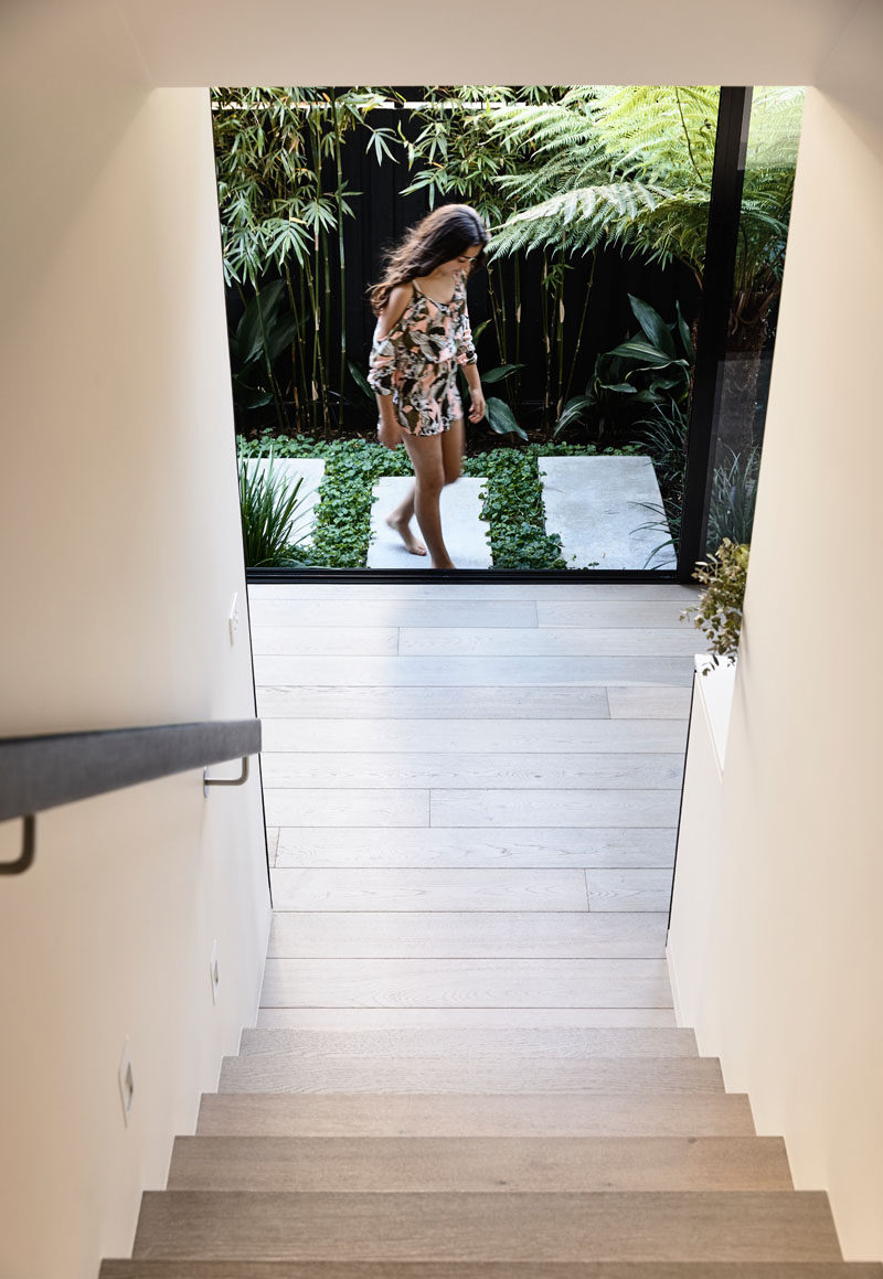 Wood stairs with views of a side courtyard lead to the upper floor of this modern house. #Stairs #Landscaping