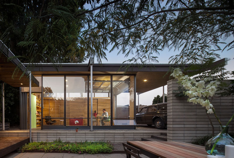 This modern backyard studio has floor-to-ceiling glass walls and a carport. #ModernBackyardStudio #Architecture