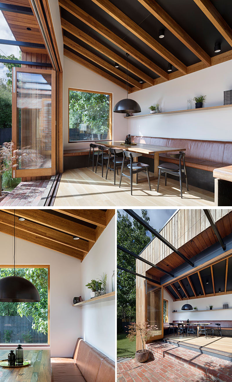 This contemporary house addition features restaurant style banquette seating that extends from the kitchen bench, while a large window provides views of the trees. Click through to see more photos. #BanquetteSeating #BanquetteDining #DiningRoom