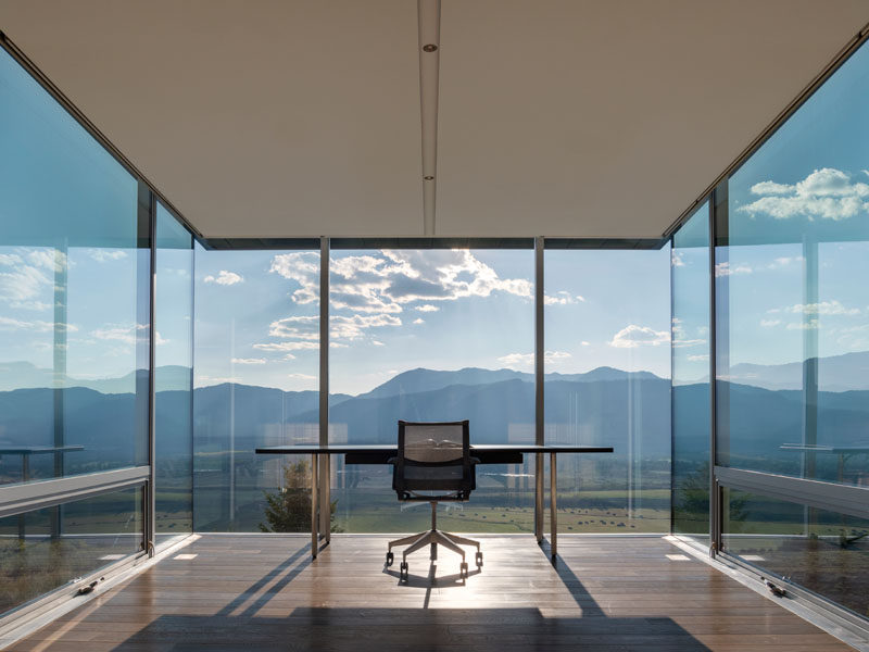 This modern house has a cantilevered office with floor-to-ceiling glass windows and uninterrupted views of the mountains. Click through to see more photos. #ModernArchitecture #ModernHouse #Cantilever #HomeOffice #Windows