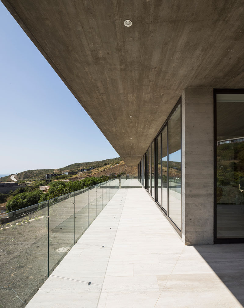 Sliding glass doors open all of the rooms of this modern concrete house onto the balcony. Click through to see more photos of this house. #Balcony #GlassRailing #ConcreteHouse