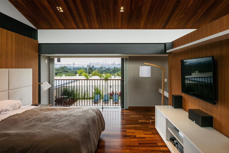 This modern bedroom has sliding doors that open to reveal a small balcony that overlooks the backyard and swimming pool below. #ModernBedroom #Balcony