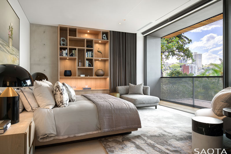 This modern bedroom has a sliding glass door that opens up to a small balcony. #ModernBedroom #WoodShelving #Balcony