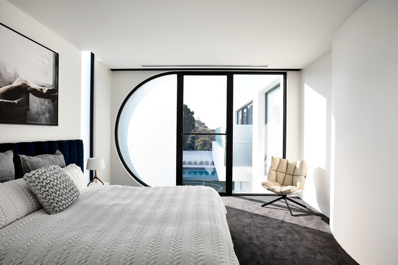 This modern bedroom features a half-circle window that's frosted to provide some privacy without blocking the light. Click through to see more photos of this modern house. #ModernBedroom #Windows #CurvedWindow #BedroomDesign