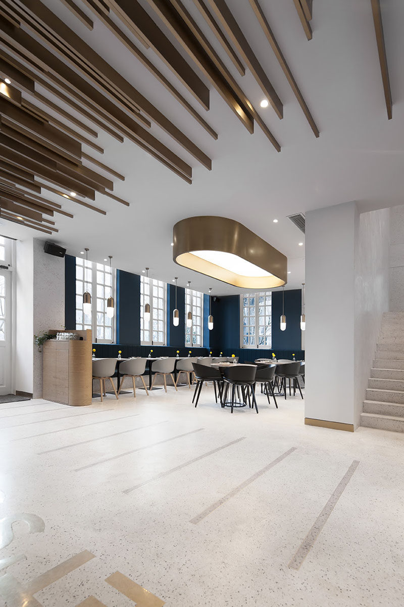 In this modern cafe, dark blue walls match the dark blue banquette seating that wraps around the seating area, creating a striking contrast to the white walls and ceiling. #ModernCafe #BlueAccentWalls