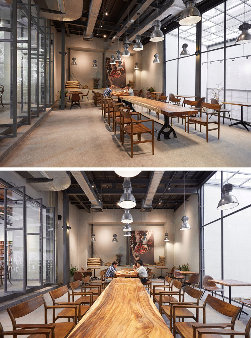 This modern coffee house a space set up for larger groups of people with a long 10 person table. Natural light from skylights above the garden filter through the black framed windows, that also provide a view of the garden below. #CoffeeHouse #CoffeeShop