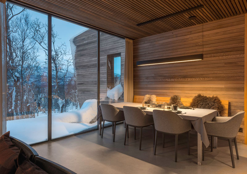 In this modern dining room, a long and horizontal pendant light hangs above the dining table, while the windows add natural light to the room.  #DiningRoom