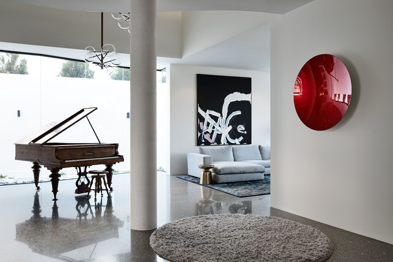 This foyer has a 2-storey atrium space that literally cuts through the house forming a formal lounge and piano room. Click through to see more photos of the house. #ModernFoyer #InteriorDesign #FormalLounge