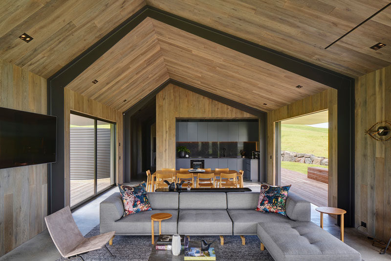 This modern guest house has a vaulted ceiling, an open plan living / dining and kitchen area, and sliding glass doors that open to decks. Click through to see more photos of this guest house #OpenPlanInterior #ModernInteriorDesign #LivingRoom #DiningRoom #Kitchen #VaultedCeiling