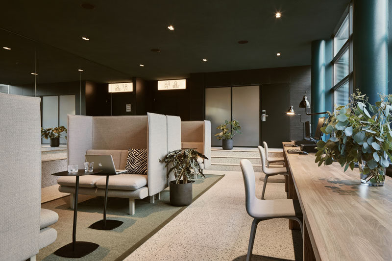 In this work area within a hotel, comfortable booths are paired with small laptop tables, while beside the windows, there's a long wood table. #HotelDesign #Workspace