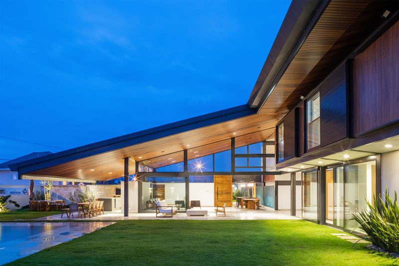 Obra Arquitetos have designed a new modern house in Sao Paulo, Brazil, that has a large sloping roof that integrates the interior living spaces with the outdoor spaces. #ModernHouse #ModernArchitecture