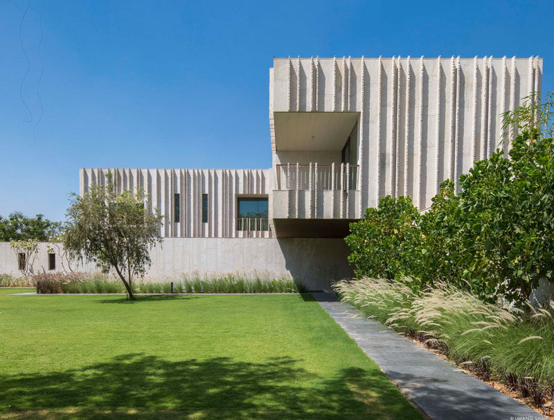 SPASM Design have recently completed a new modern house in Ahmedabad, India, that features an exterior of Dhrangadhra stone, and a simple cross layout. #Architecture #FrontDoor #ModernHouse