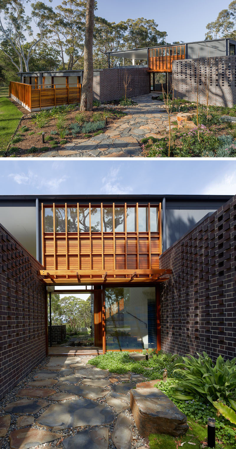 The entryway of this modern house is by emphasizing the landscape design, where the designers used smaller plants, larger trees that will grow over time, and a stone path that leads to the front door. Click through to see more photos of this modern house. #Landscaping #LandscapeDesign #Garden #StonePath #GardenPath