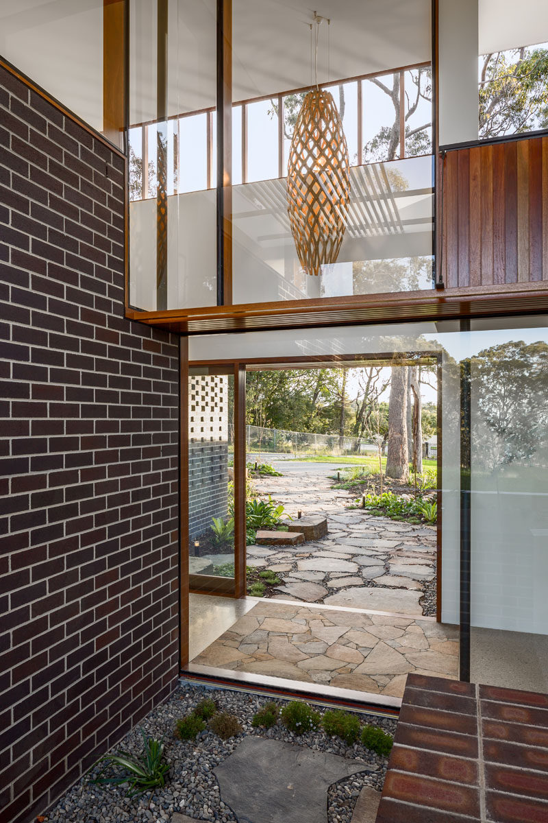 As this entryway has plenty of glass, the sliding glass front door allows for seamless views through to the backyard and outdoor space. Click through to see more photos of this modern house. #Windows #Entryway #FrontDoor