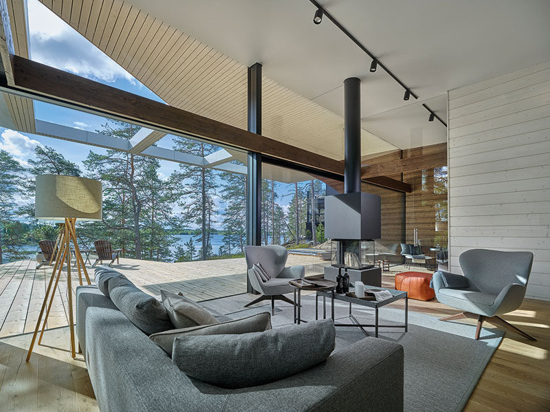 The interior of this modern house is bright and open with large glass walls, white walls and ceiling, and in the living room there's a fire for cool nights. #ModernLivingRoom