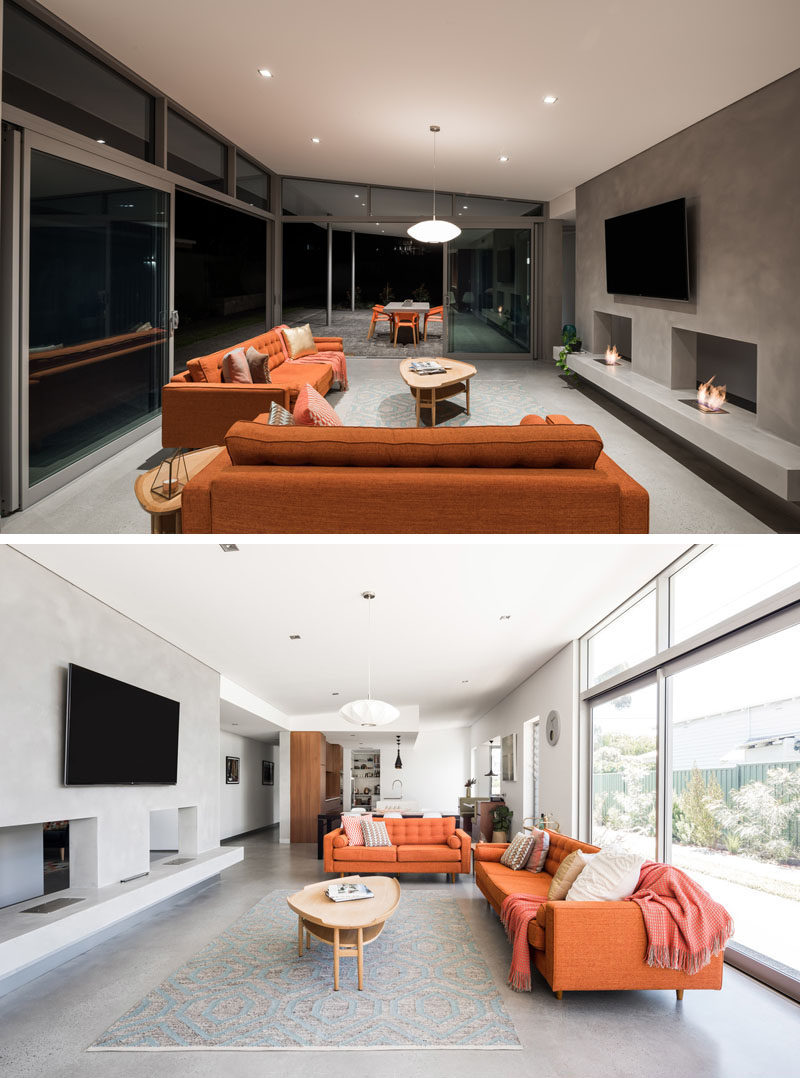 This modern house has an open living area with two fireplaces, that's flooded in daylight during the day and has a seamless integration with the outdoor living area by the carport. #ModernLivingRoom #Fireplace