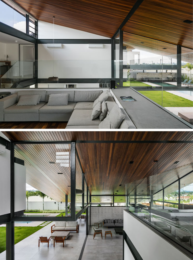 At the top of the stairs in this modern house, is a secondary lounge area, that has glass partitions to allow users to see the full wood ceiling and the spaces below. #LivingRoom #Ceiling #RoofLine