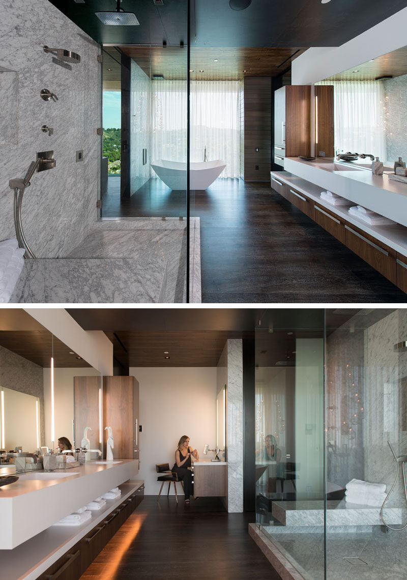 In this modern master bathroom, there's a freestanding bath that sits beside the window, as well as a glass enclosed Carrara marble shower and quartz counters. #MasterBathroom #ModernBathroom