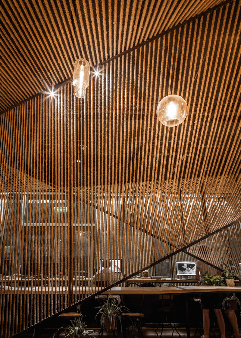 Rope has been used to create partitions and cover the original beam-column system in this modern workplace, and when combined with lighting, it helps to create a comfortable and friendly space. Click through to see more photos of this modern office design. #RopePartition #ModernWorkplace #RopeScreen #ModernOffice