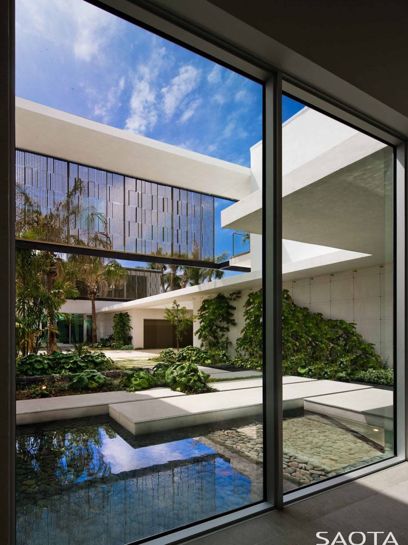 Large windows in this modern house provide a view of a water feature, garden and path. #Windows #Architecture