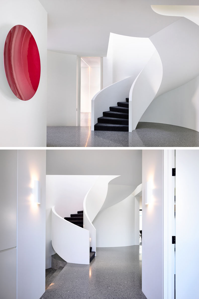 This modern house features a white spiral staircase with black stair treads. Click through to see more photos of this modern house. #Stairs #SpiralStairs #PolishedConcreteFlooring