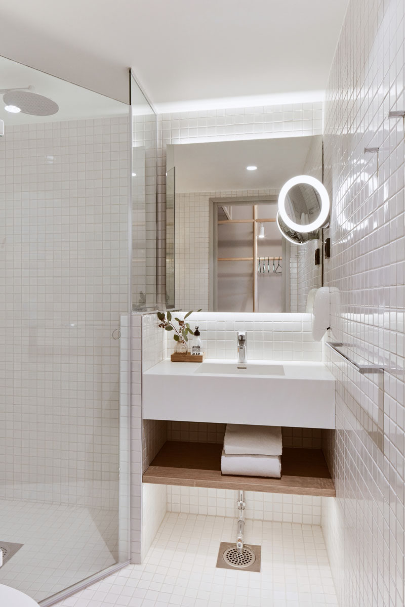 This modern bathroom has floor-to-ceiling white tiles and a backlit mirror. #WhiteBathroom