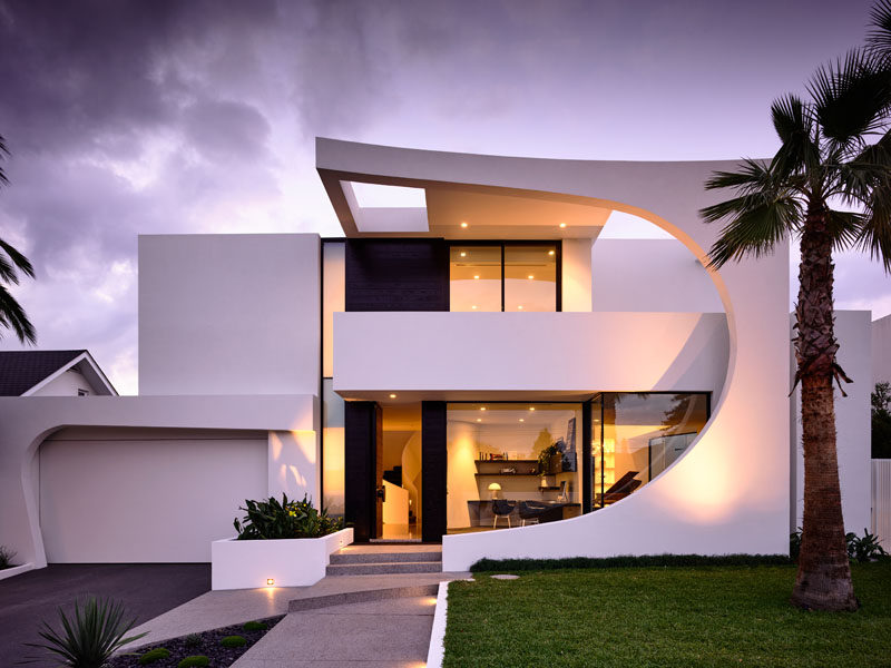 This modern house features a striking facade with a 2 storey curved section made from concrete that was cast in place. Click through to see more photos of this house. #ModernHouse #ModernArchitecture #HouseDesign #Facade #AustralianArchitecture #Landscaping