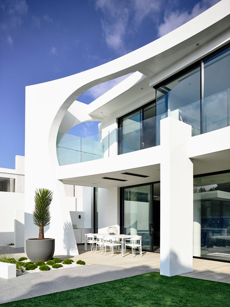 This modern house has a covered outdoor dining area. Click through to see more photos of this modern house. #Architecture #OutdoorDining #WoodDeck #Landscaping #ModernHouse