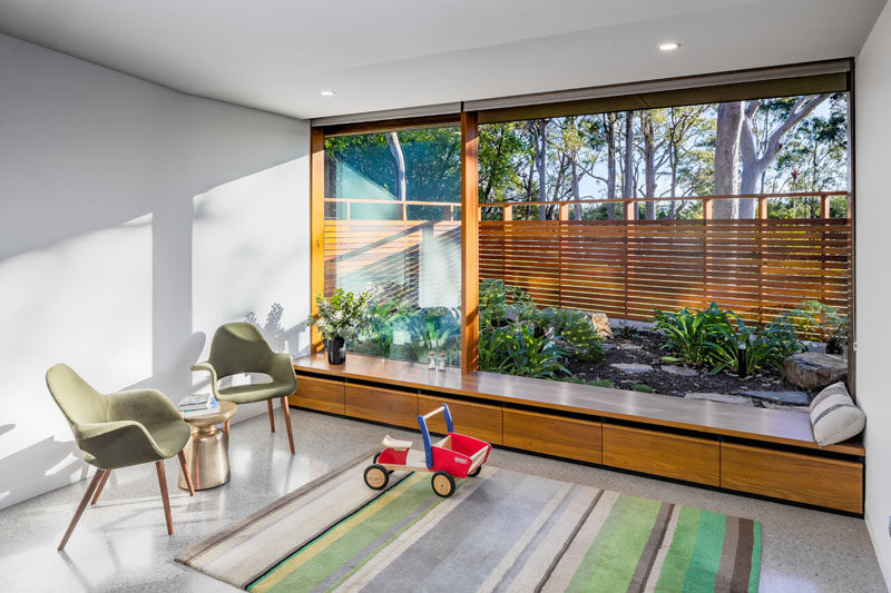 This small open room has a built-in window seat that sits next to a small garden. Click through to see more photos of this modern house. #WindowSeat #Garden #Landscaping #InteriorDesign