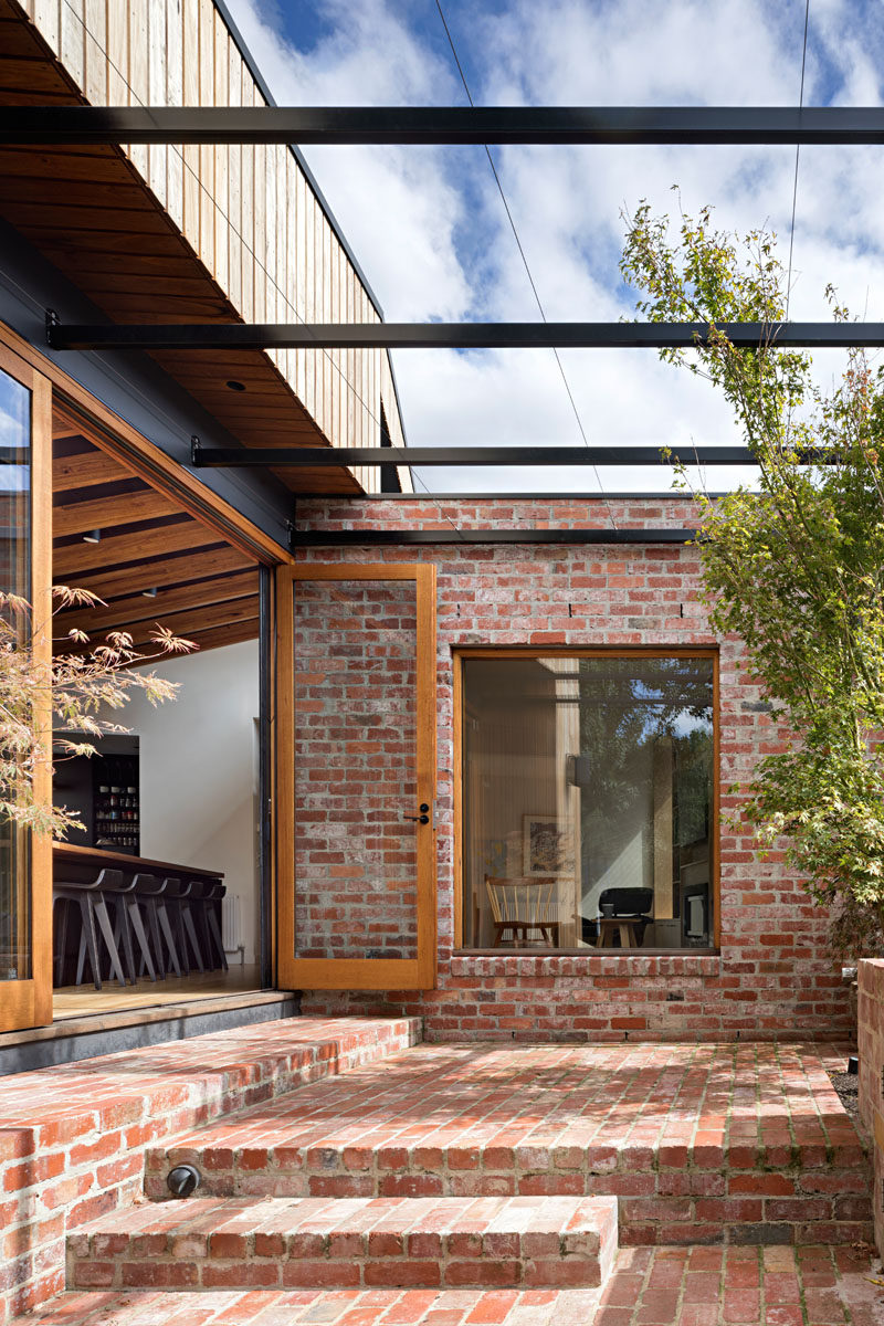 Wood framed glass doors open the dining area of this extention to the backyard, where there's a brick patio, pool and yard. Click through to see more photos. #BrickPatio #Patio #Architecture #OutdoorSpace