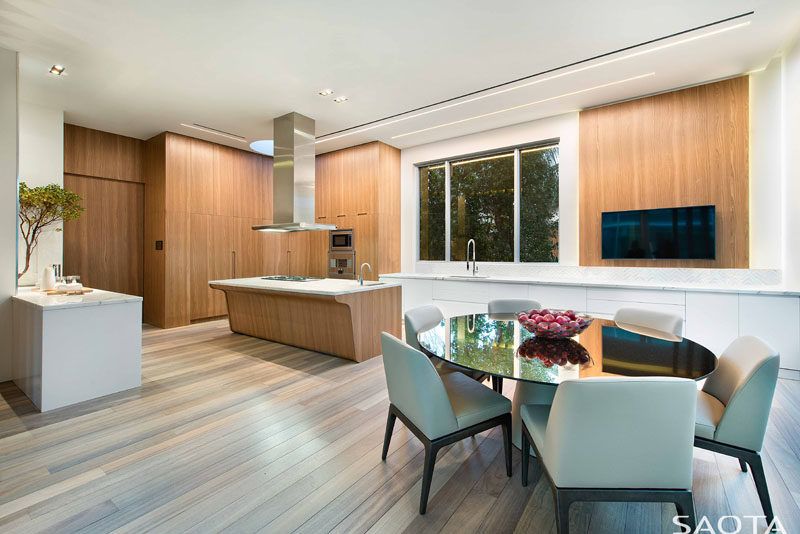 This modern kitchen uses a combination of wood and white cabinets with white countertops. #WoodKitchen