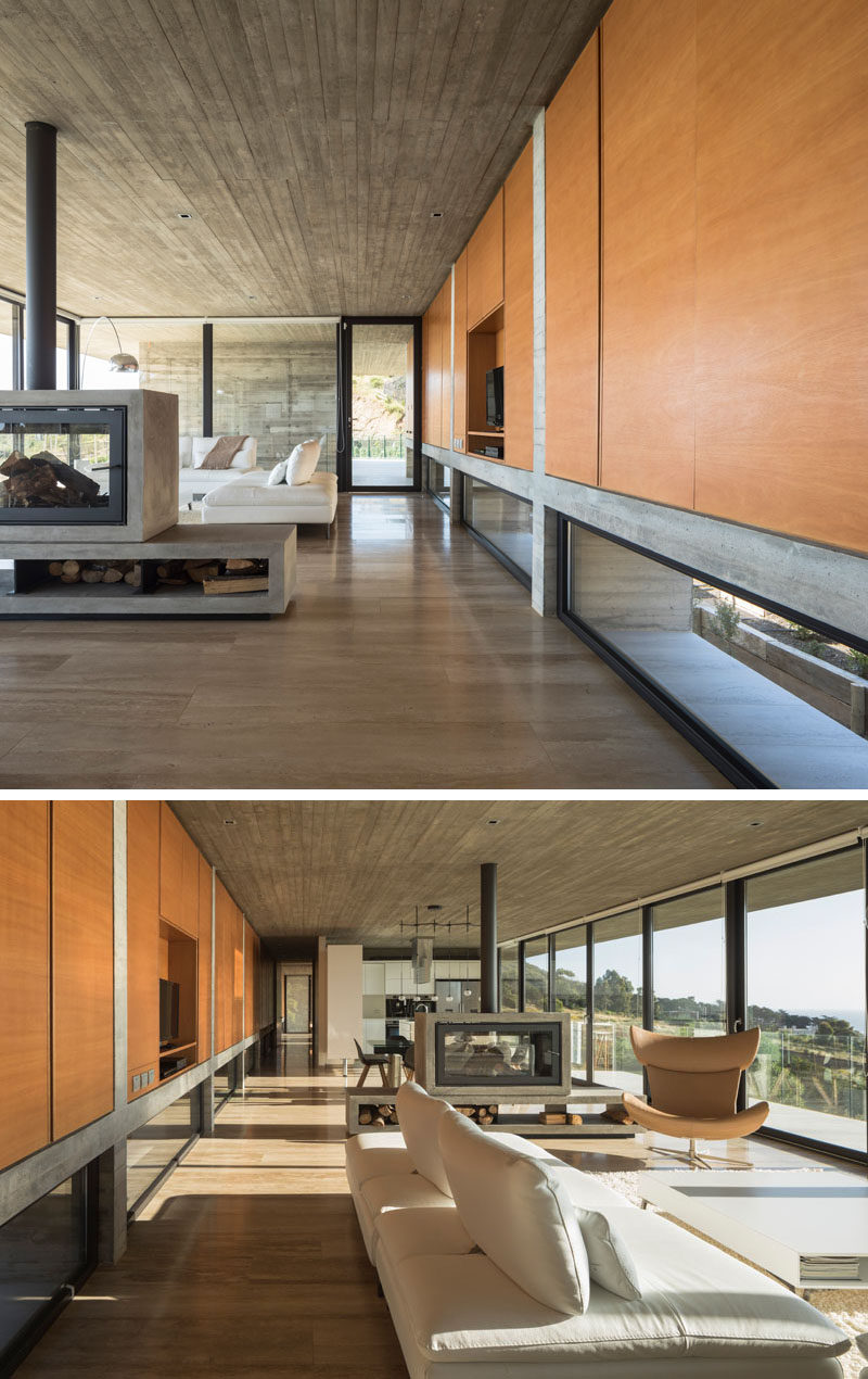 Inside this modern house, the concrete structure is heavily featured, while a wall of wood cabinetry and wood flooring add a natural touch to the interior. Click through to see more photos of this modern house. #Cabinetry #ConcreteHouse #Fireplace #WoodFlooring