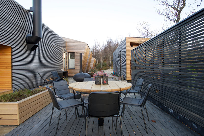 This modern house has an outdoor dining space with a fireplace and outdoor kitchen. #OutdoorSpace #Deck